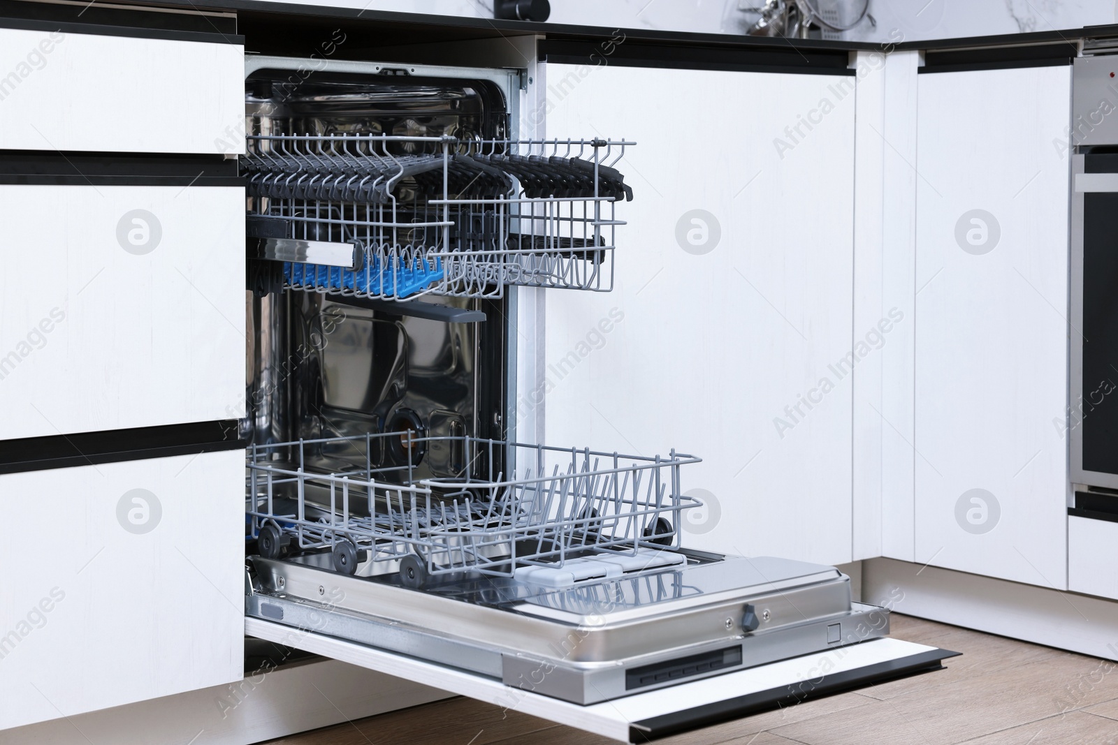 Photo of Open clean empty dishwasher in kitchen. Home appliance