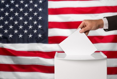 Image of Man putting his vote into ballot box against national flag of United States, closeup. Space for text