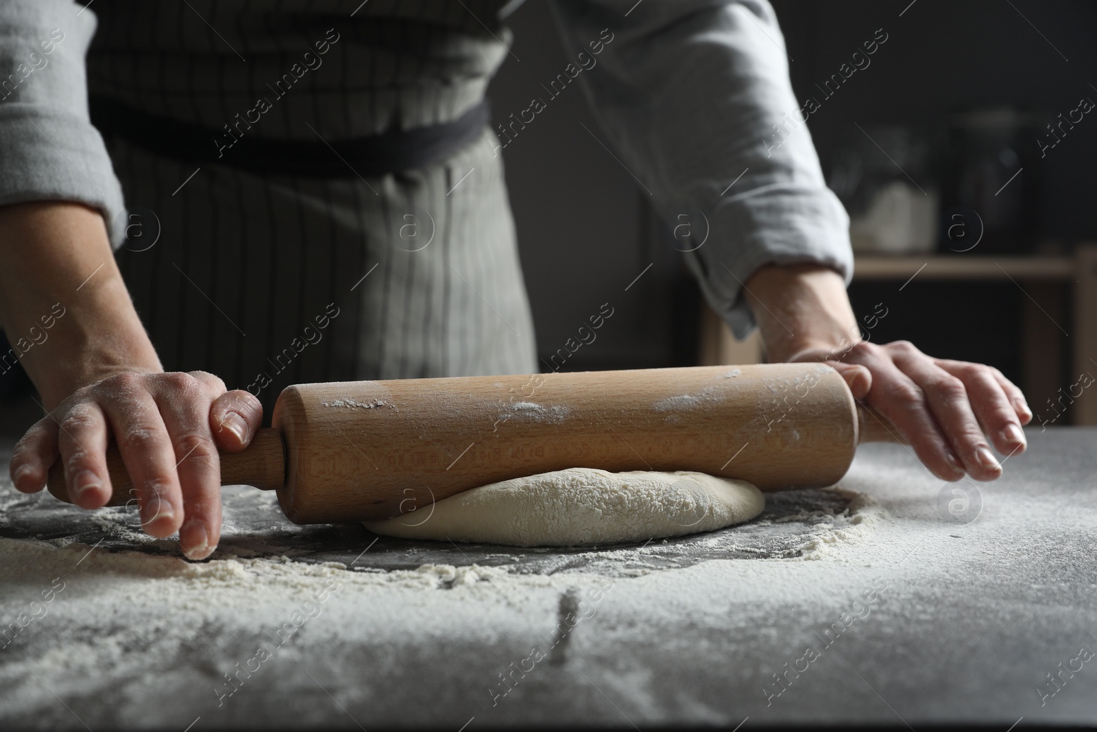 Photo of Woman rolling pizza dough with pin at table, closeup