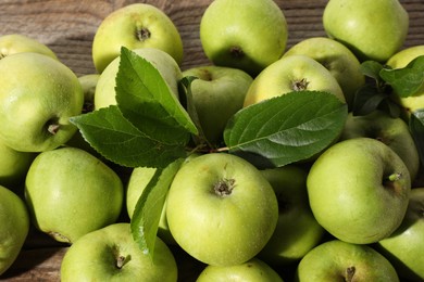 Many fresh apples and leaves on wooden table, above view