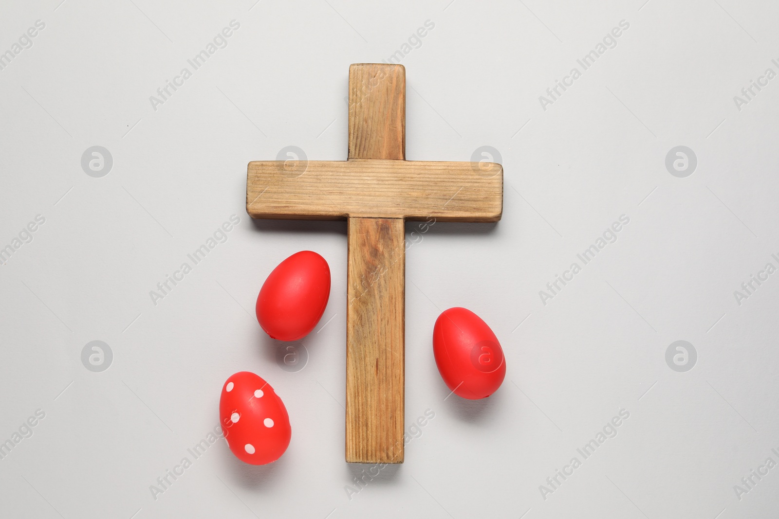 Photo of Wooden cross and painted Easter eggs on light grey background, flat lay