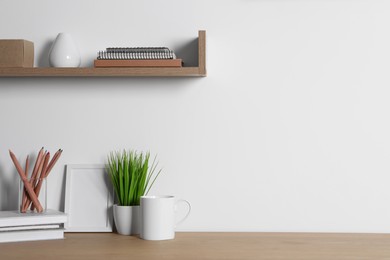 Photo of Comfortable workplace with wooden desk near white wall at home