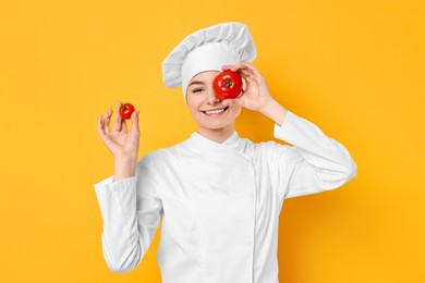 Photo of Professional chef with fresh tomatoes having fun on yellow background