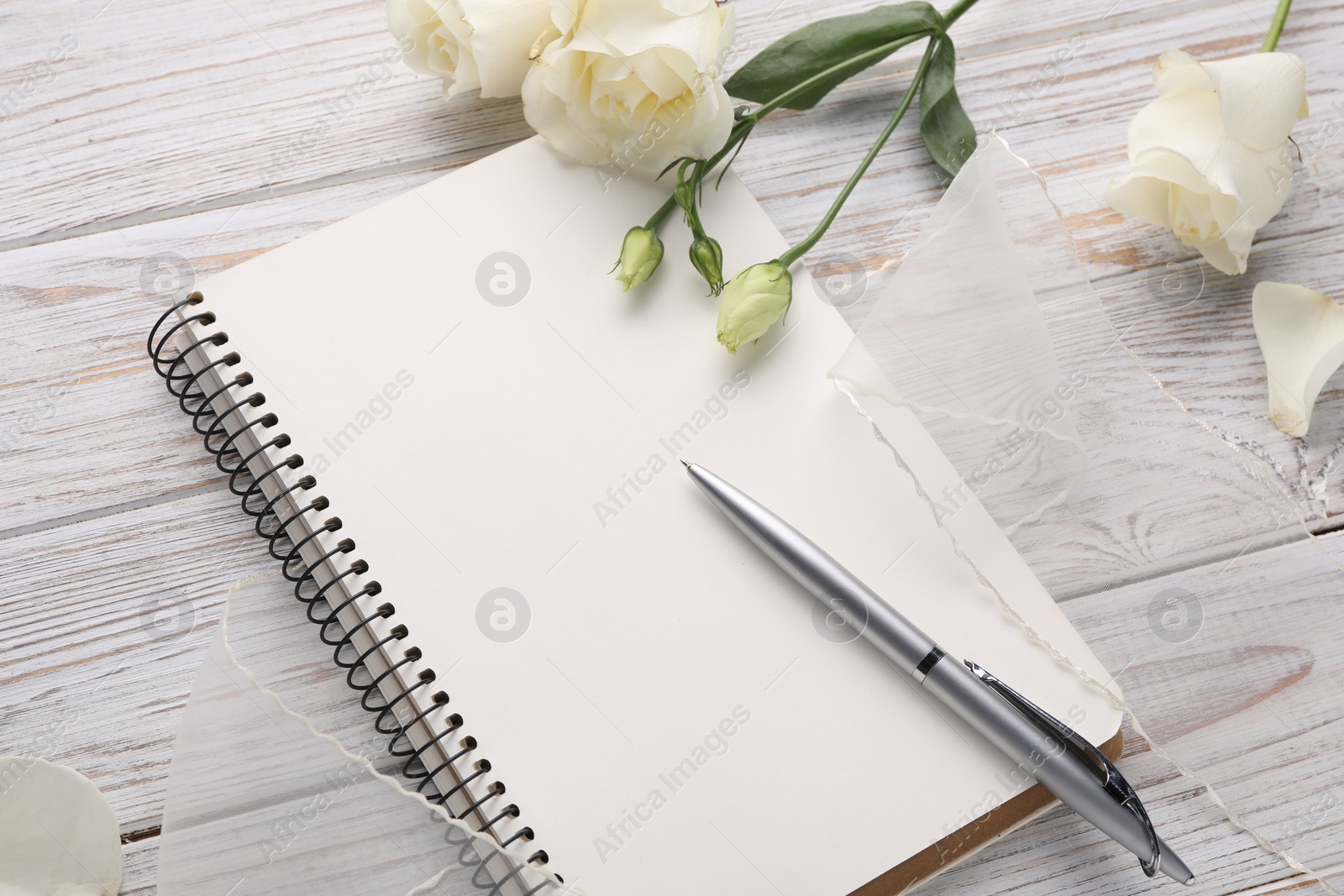 Photo of Guest list. Notebook, pen, rose flowers and ribbon on wooden background, above view