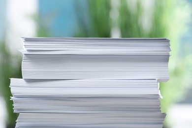 Photo of Stack of paper sheets against blurred background, closeup