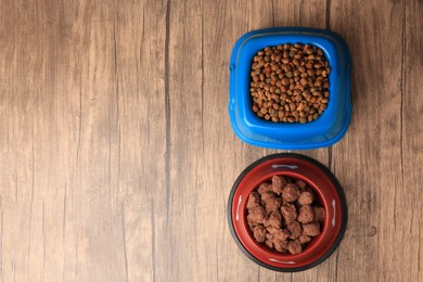 Dry and wet pet food in feeding bowls on wooden background, flat lay. Space for text