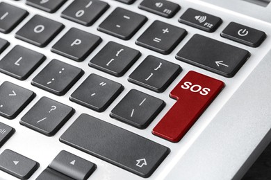 Image of Red button with word SOS on computer keyboard, closeup. Rescue concept