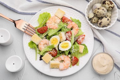 Photo of Delicious Caesar salad with shrimps and fork served on white textured table, flat lay