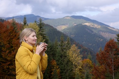 Photo of Young woman with mug of hot drink in mountains