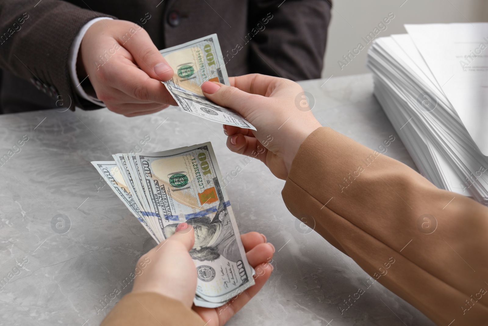 Photo of Woman giving money to man at light grey table, closeup. Currency exchange