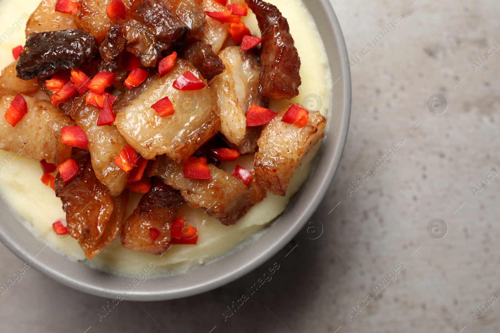 Photo of Potato puree and tasty fried cracklings on light table, top view with space for text. Cooked pork lard