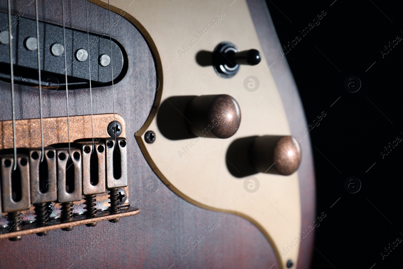 Photo of Modern electric guitar in darkness, closeup view