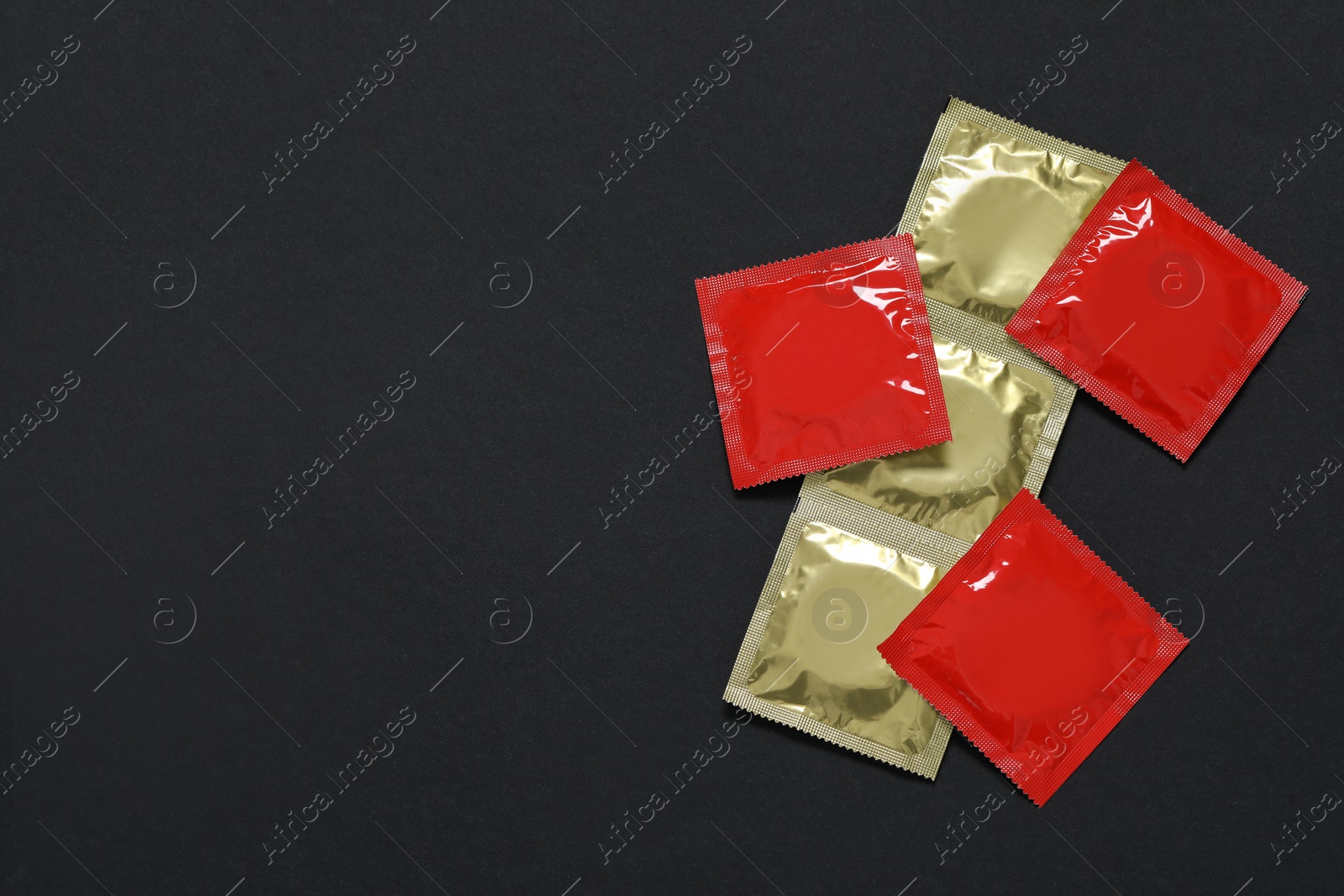 Photo of Condom packages on black background, flat lay and space for text. Safe sex