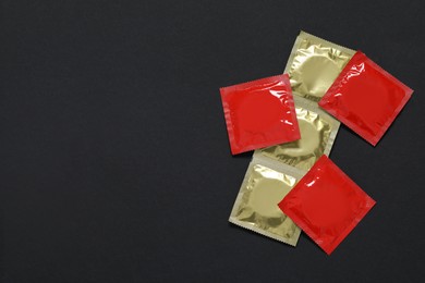 Photo of Condom packages on black background, flat lay and space for text. Safe sex