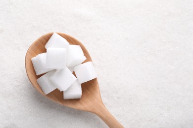 Photo of Different types of white sugar and spoon as background, top view. Space for text