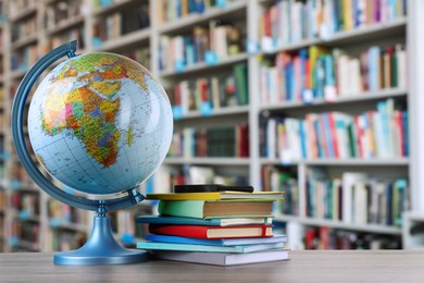 Image of Globe, school supplies and magnifying glass on wooden table in library. Space for text