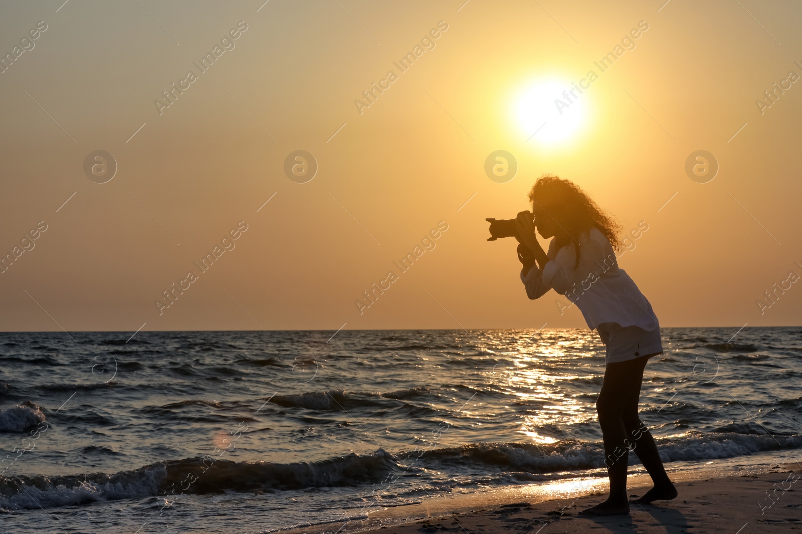 Photo of Photographer taking photo of sea with professional camera at sunset