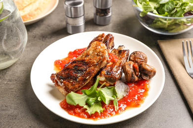 Photo of Delicious grilled ribs served on grey table