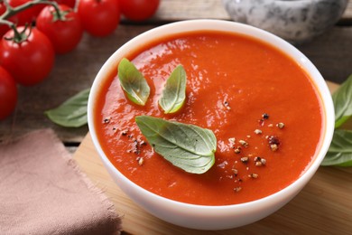 Photo of Delicious tomato soup with basil and spices on table, closeup