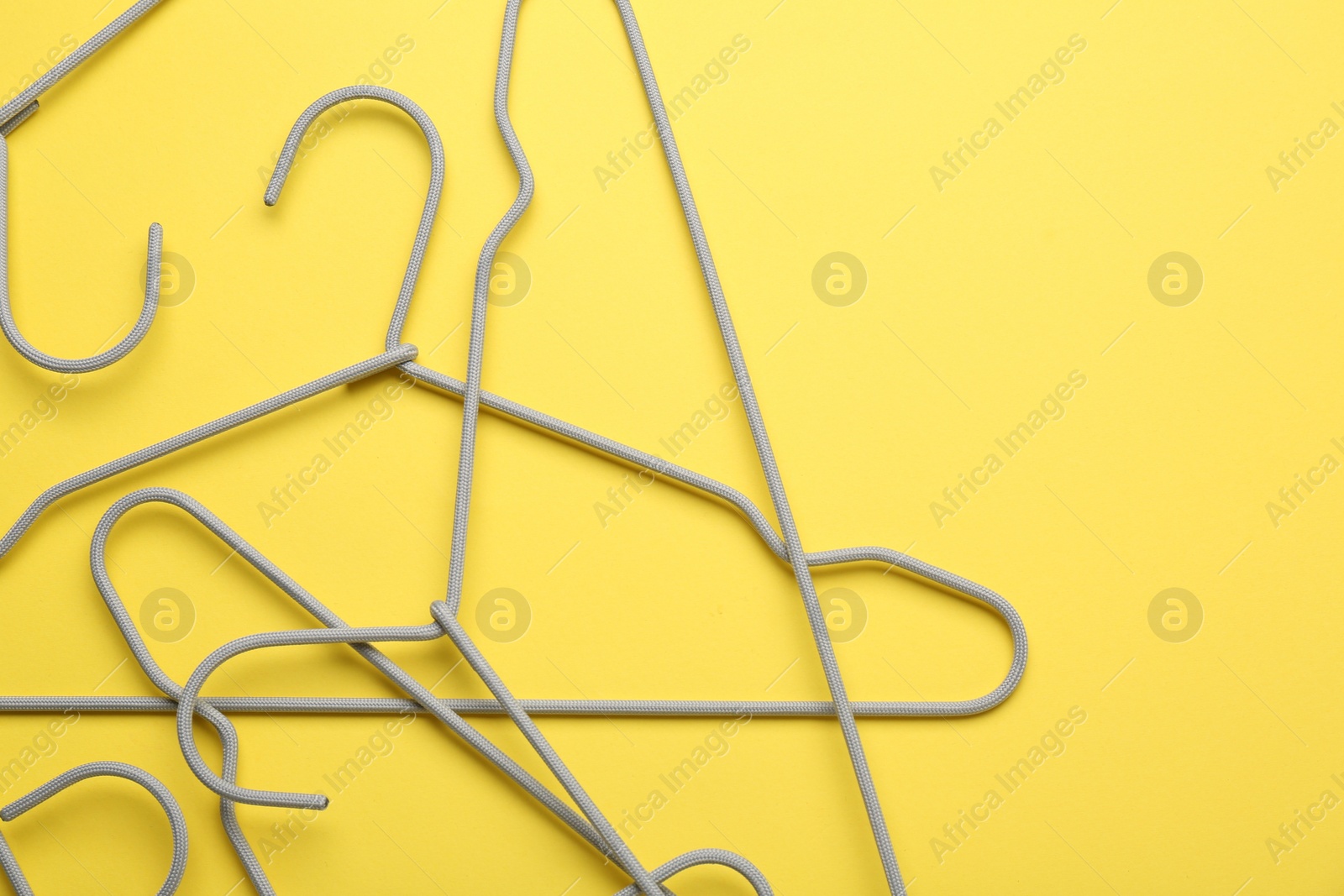 Photo of Empty hangers on yellow background, top view. Space for text