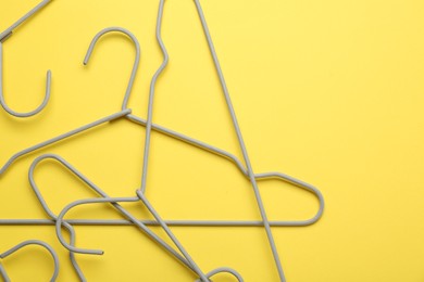 Empty hangers on yellow background, top view. Space for text