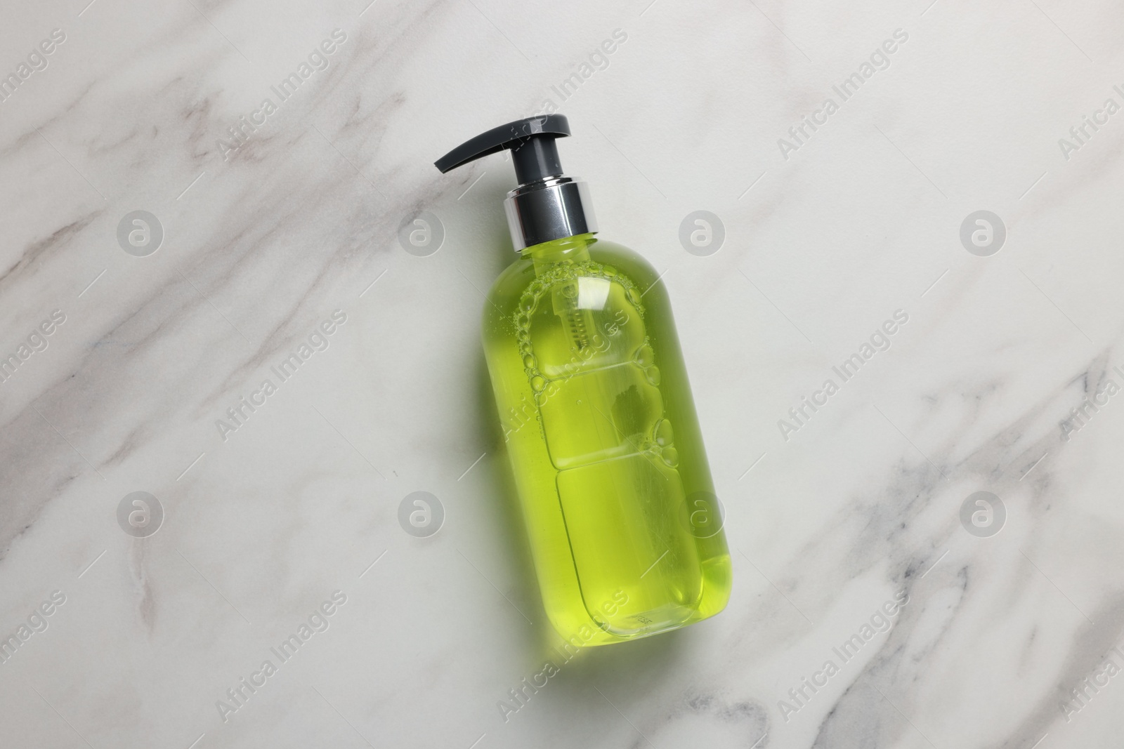 Photo of Dispenser of liquid soap on white marble table, top view