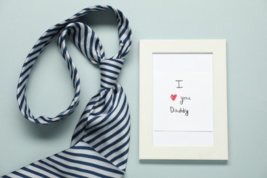 Photo of Father's day celebration. Photo frame with phrase I Love You Daddy and necktie on grey background, flat lay