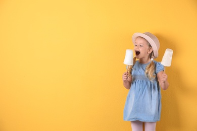 Cute little girl with cotton candies on color background. Space for text