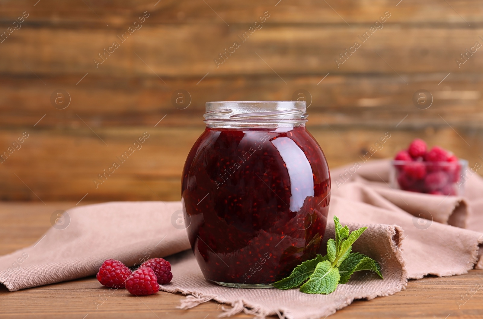 Photo of Jar with delicious raspberry jam on table