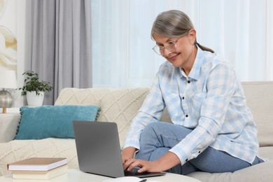 Photo of Beautiful senior woman using laptop at home