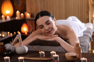 Photo of Spa therapy. Beautiful young woman lying on massage table in salon