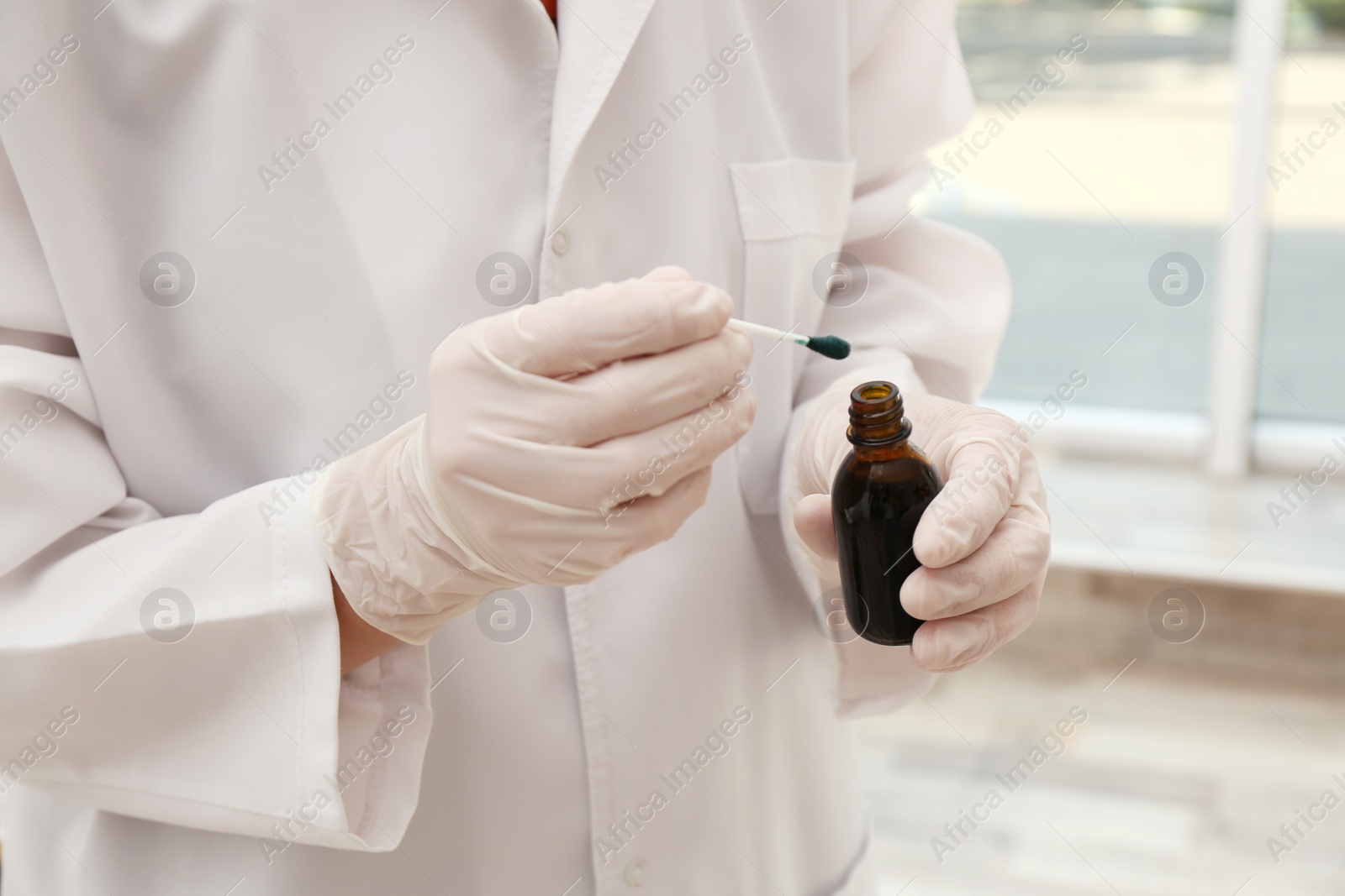Photo of Doctor holding bottle of brilliant green and cotton bud indoors, closeup