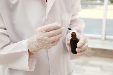 Doctor holding bottle of brilliant green and cotton bud indoors, closeup