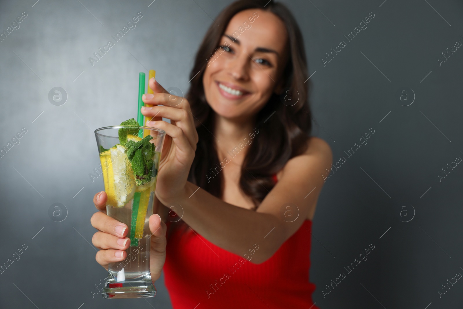 Photo of Young woman with refreshing drink on dark grey background, closeup