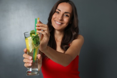 Young woman with refreshing drink on dark grey background, closeup