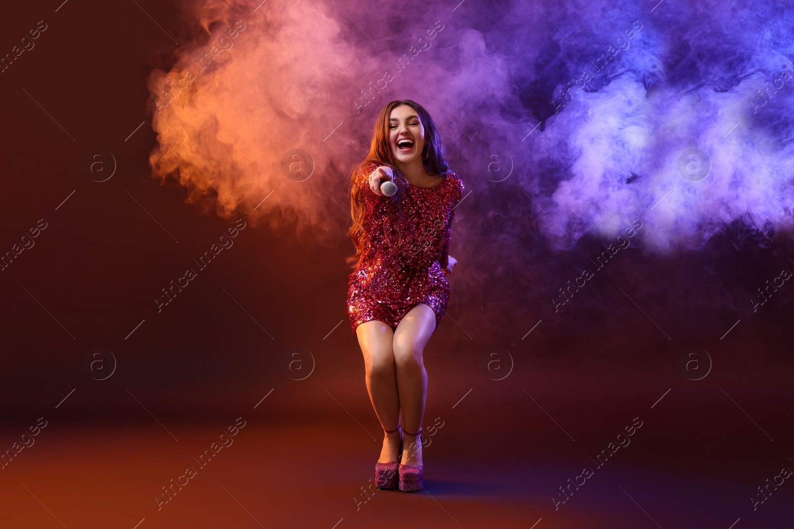 Photo of Emotional singer giving microphone to others in color lights