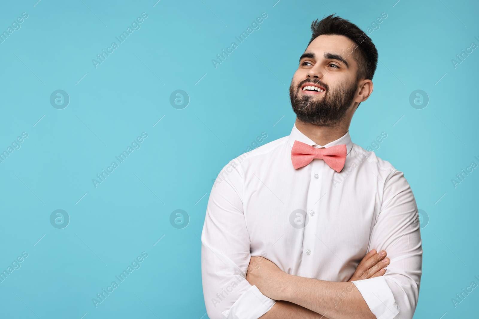 Photo of Portrait of smiling man in shirt and bow tie on light blue background. Space for text