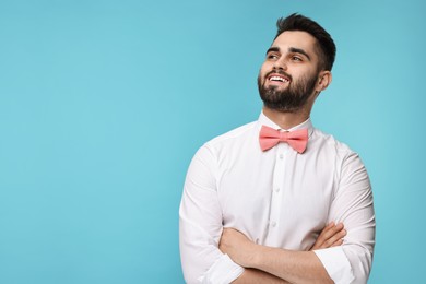 Portrait of smiling man in shirt and bow tie on light blue background. Space for text