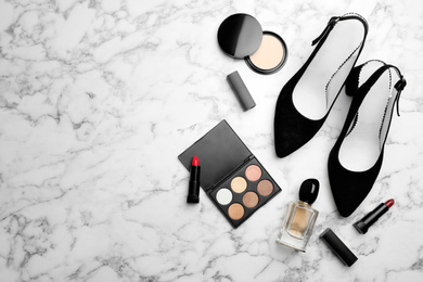 Flat lay composition with stylish shoes and cosmetics on white marble table. Space for text