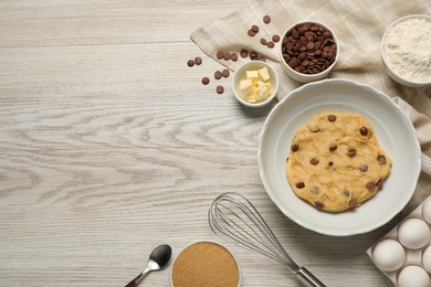 Photo of Fresh dough and different ingredients for cooking chocolate chip cookies on white wooden table, flat lay. Space for text
