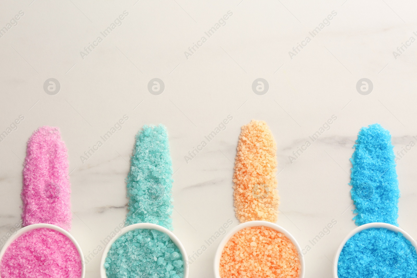 Photo of Many bowls with colorful sea salt on white marble table, flat lay. Space for text