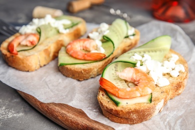 Cutting board of delicious bruschettas with shrimps on grey table