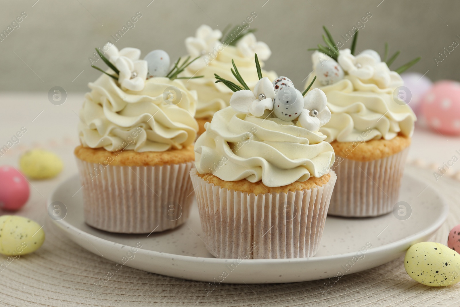 Photo of Tasty Easter cupcakes with vanilla cream and candies on table, closeup