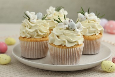 Tasty Easter cupcakes with vanilla cream and candies on table, closeup