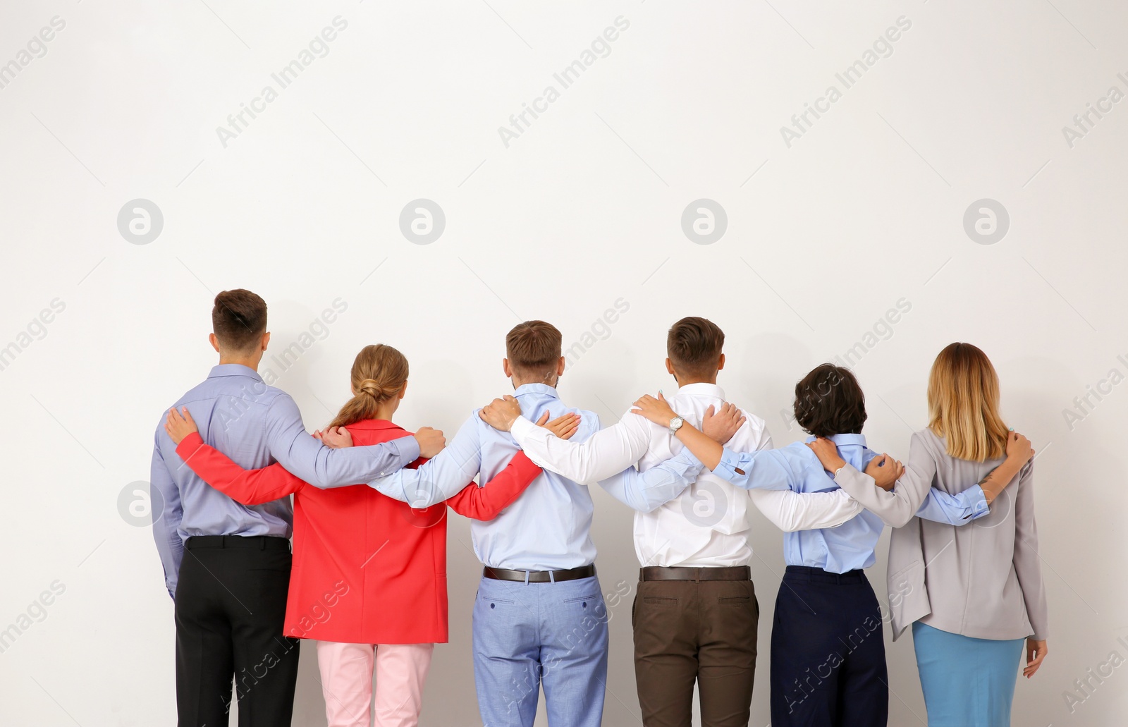 Photo of Group of young people hugging each other on light background. Teamwork concept