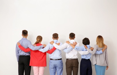 Photo of Group of young people hugging each other on light background. Teamwork concept