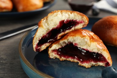 Photo of Delicious baked patties with jam and blueberry on grey table, closeup