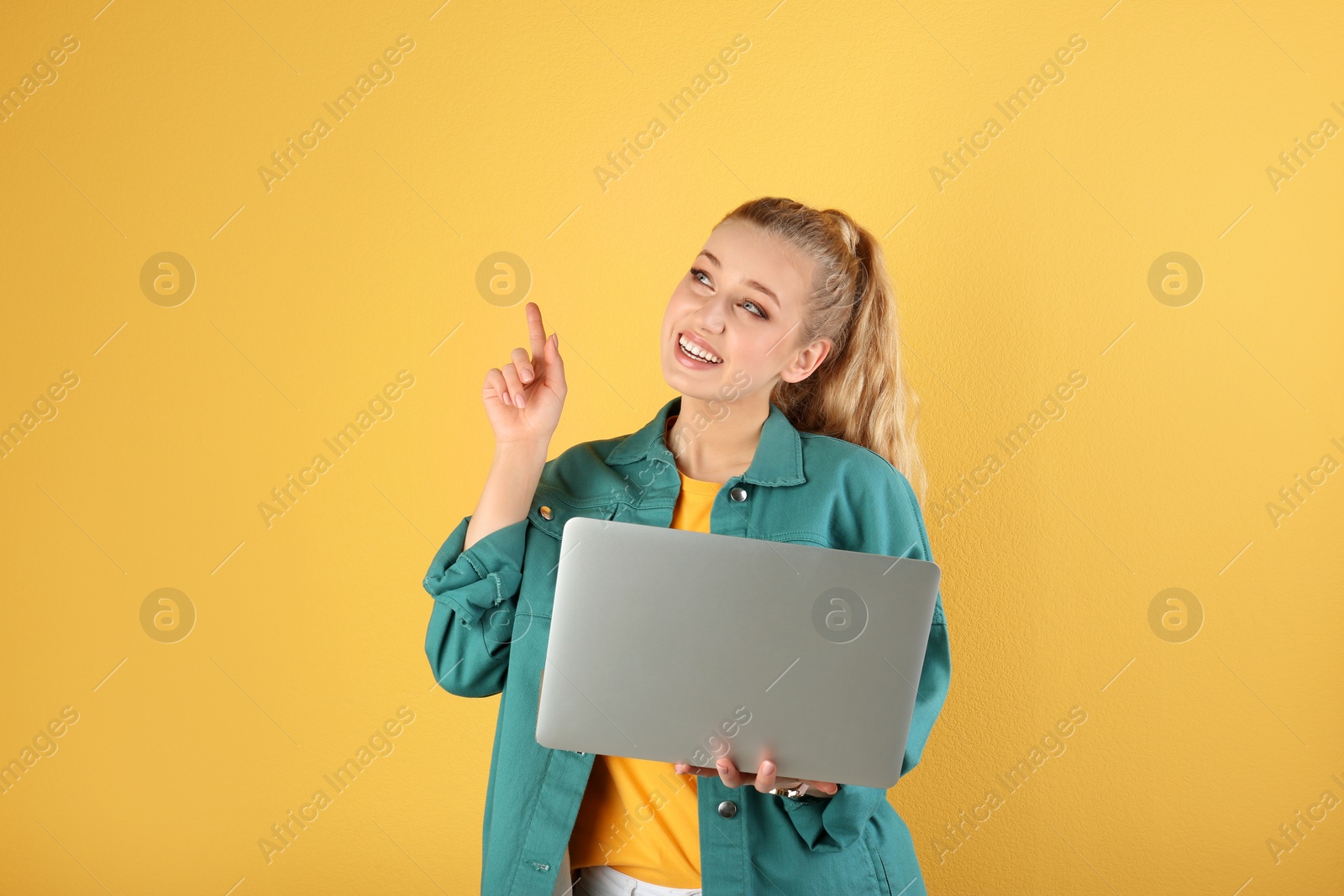 Photo of Portrait of beautiful young woman with laptop on yellow background