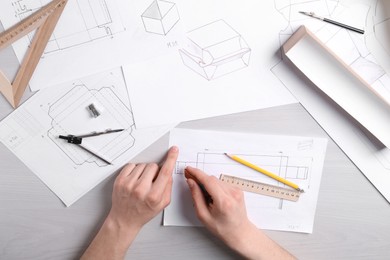 Photo of Man creating packaging design at light wooden table, top view