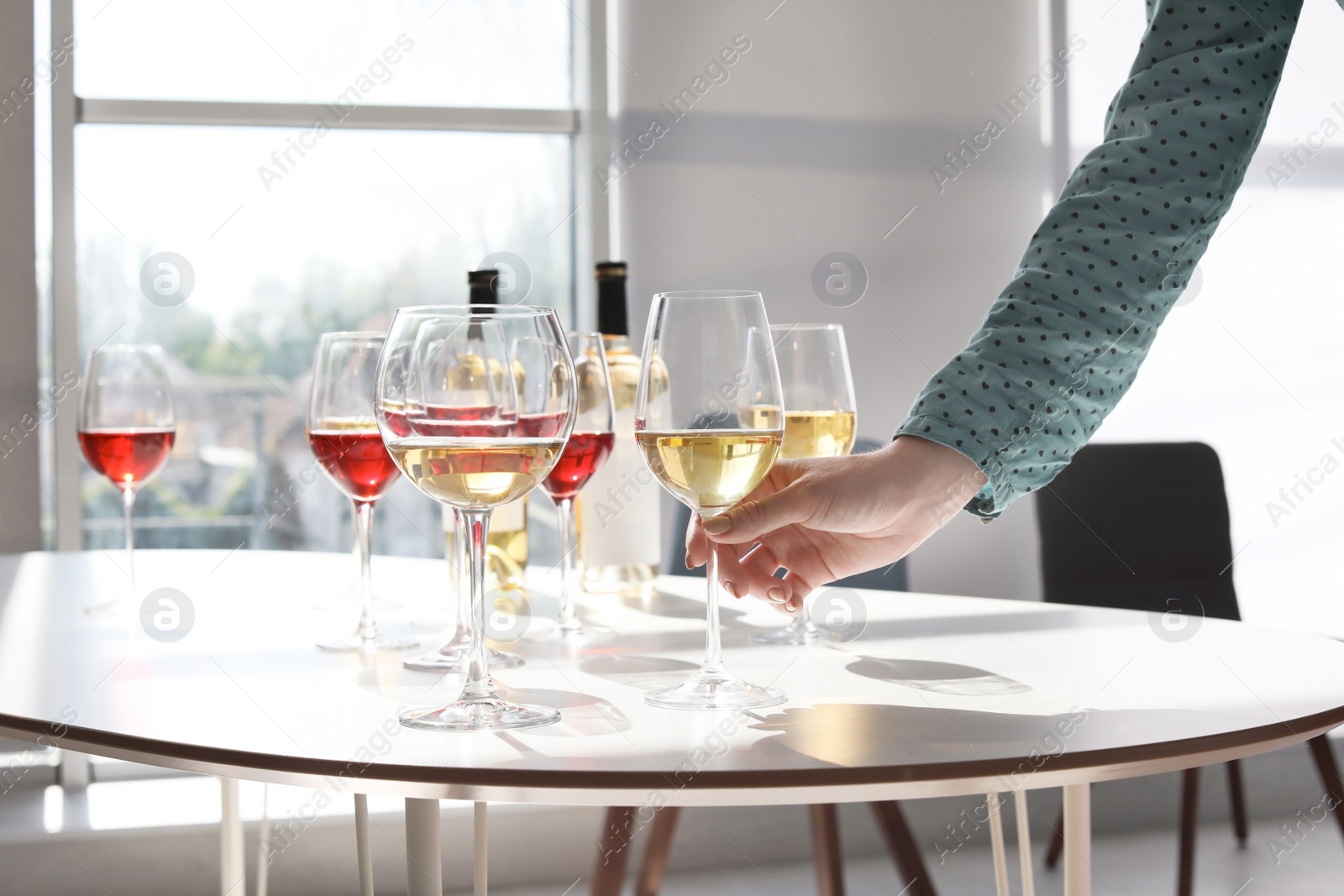 Photo of Woman taking glass of wine from table indoors